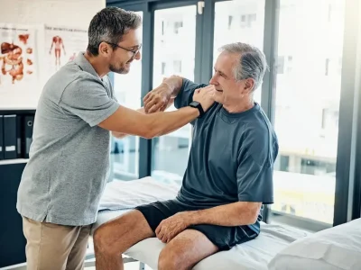 Senior,Man,,Physiotherapist,And,Stretching,Shoulder,For,Assessment,,Mobility,And