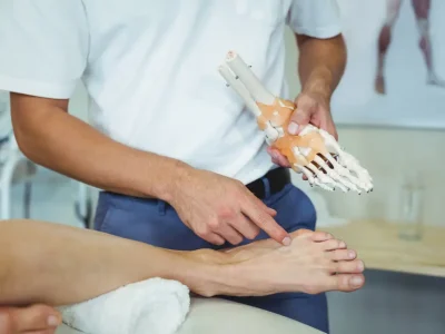 Physiotherapist,Explaining,Feet,Model,To,Patient,In,Clinic